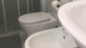 A bathroom with a toilet, bidet, and sink. - Barone Beach Hotel (Rimini)