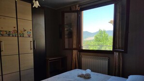 A bedroom with a bed, a window with a view of greenery and hills, a radiator, and a wardrobe with decorative stickers. - A Pochi Passi dal Chianti, Immersi nel Verde con Animali Ammessi (Cavriglia)