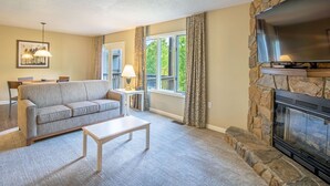 A living room with a stone fireplace, a sofa, a coffee table, and a television.