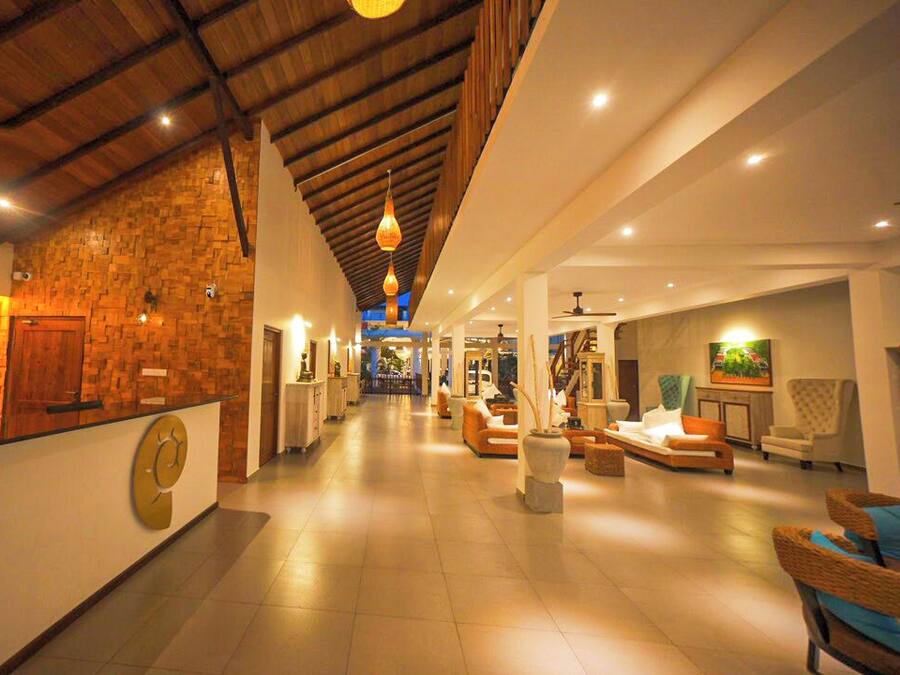 Vestíbulo de hotel con mostrador de recepción, zona de estar y escalera que conduce a los pisos superiores.