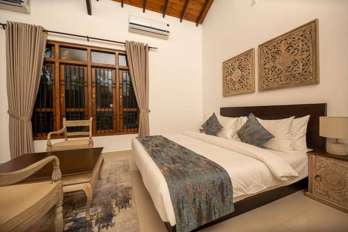 Un dormitorio con cama, escritorio, silla y ventana con cortinas.