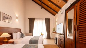 Ein Hotelzimmer mit zwei Betten, einem Fernseher, einem Schreibtisch und einem großen Spiegel.