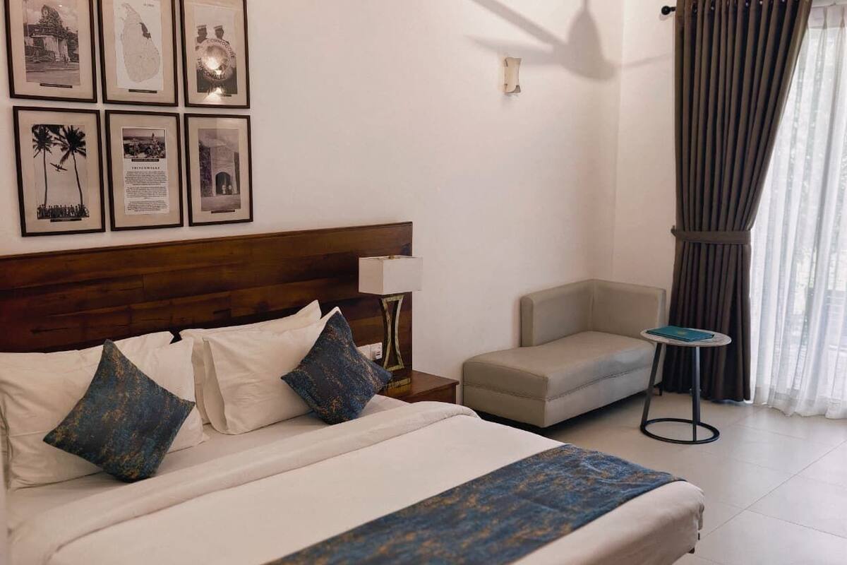 Habitación de hotel con cama, sofá, una mesita y cuadros en la pared.