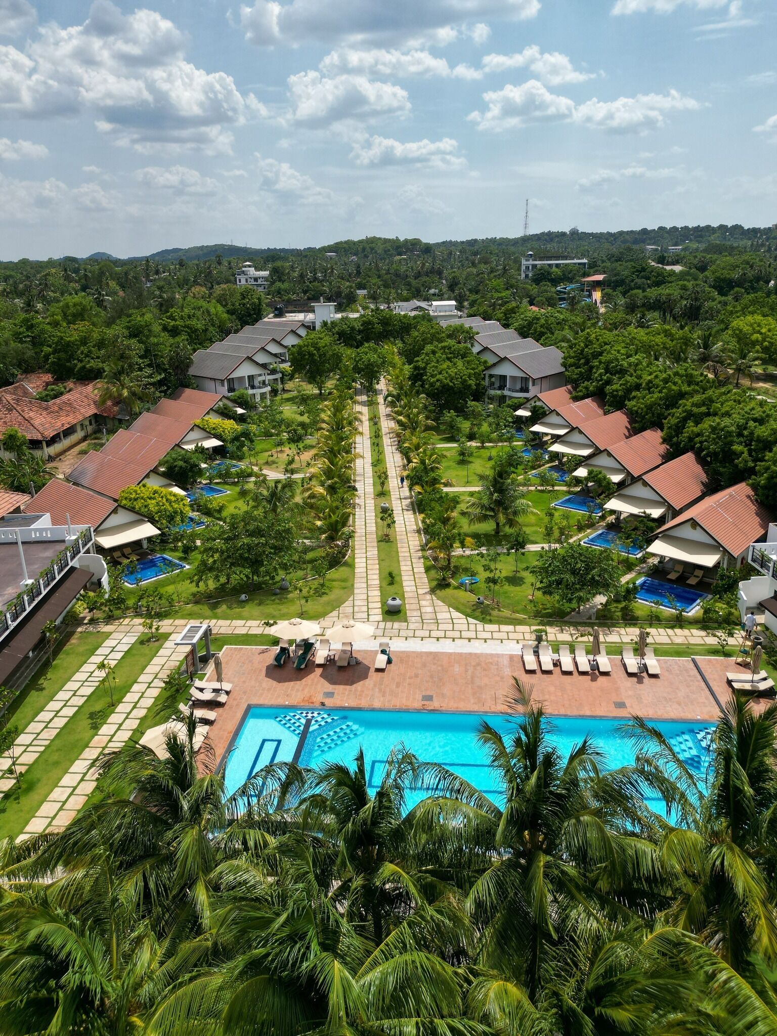 A resort with a central swimming pool, surrounded by guest rooms and lush greenery.