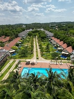 Un complejo turístico con piscina central, rodeado de habitaciones de huéspedes y abundante vegetación.