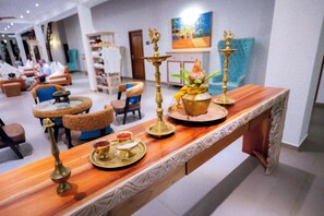 A reception area with a long wooden counter, a television, and seating arrangements including chairs and a sofa. - Uppuveli Beach by DSK (Trincomalee)