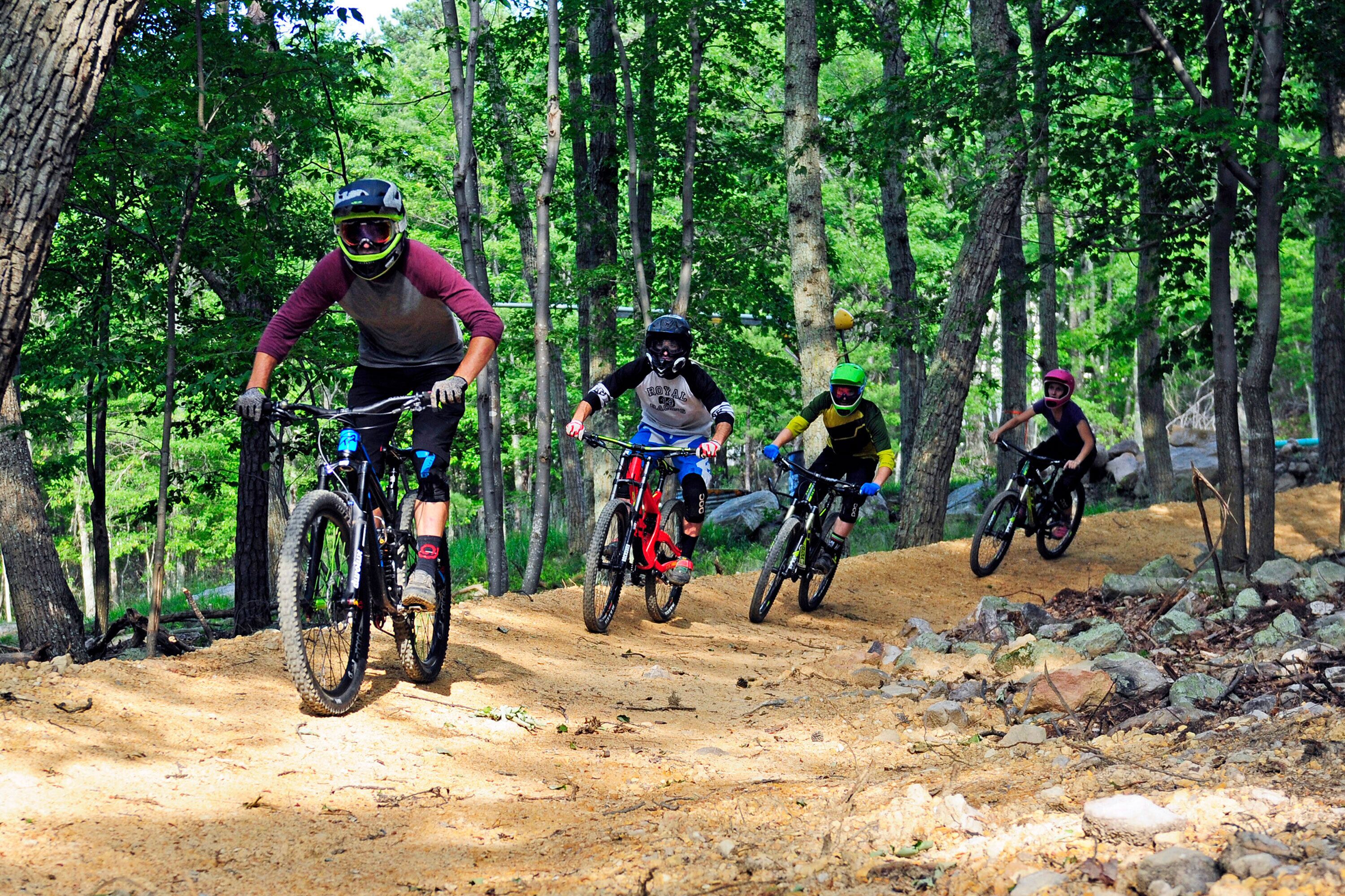 Een groep mountainbikers op een onverhard pad, omringd door bomen.