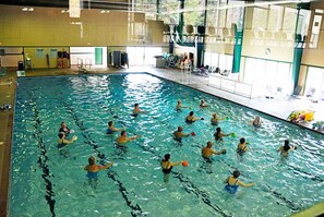 Piscina interior com várias pistas de natação, um trampolim e uma área para espectadores.