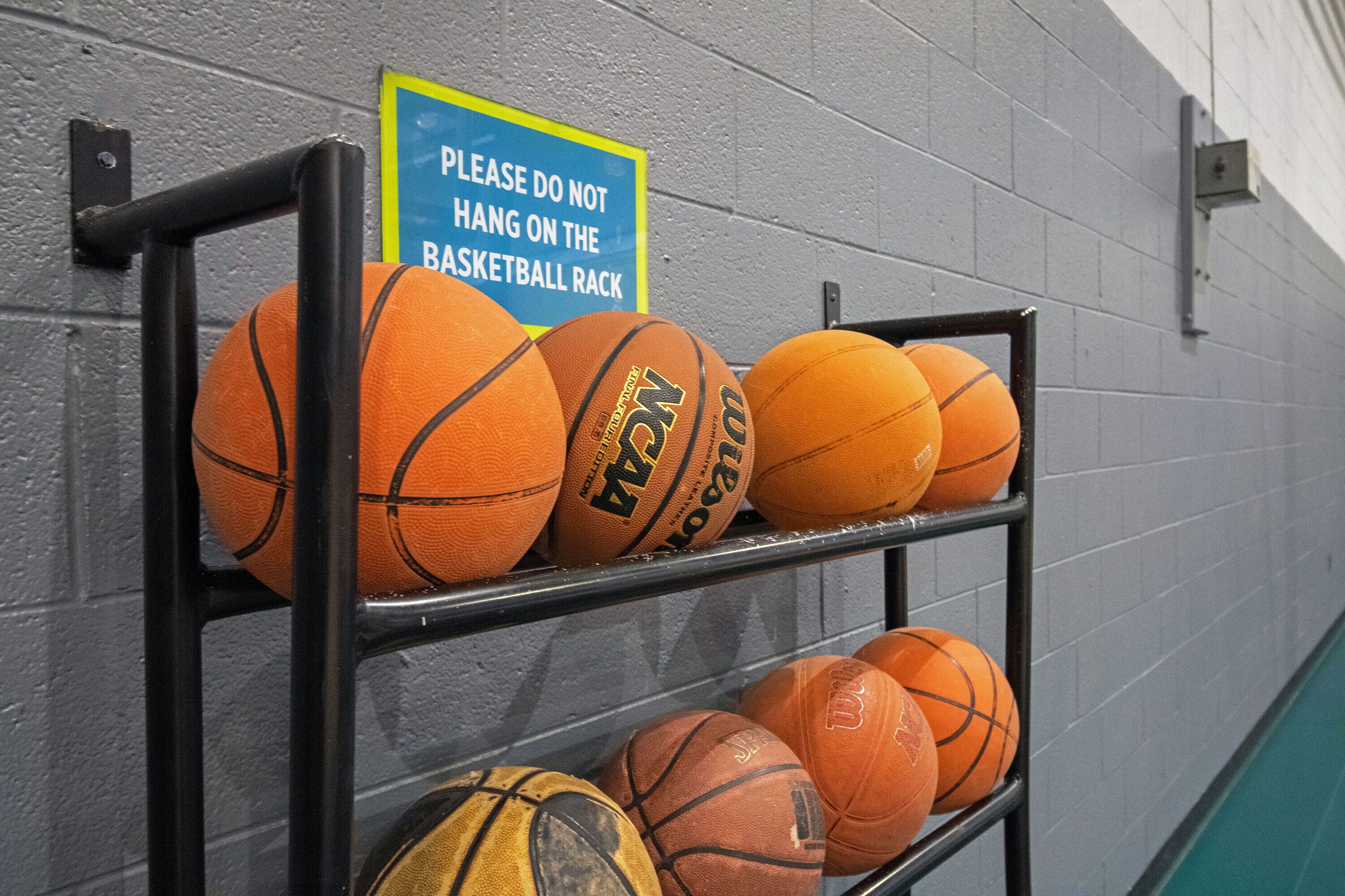 A rack with multiple basketballs against a wall.