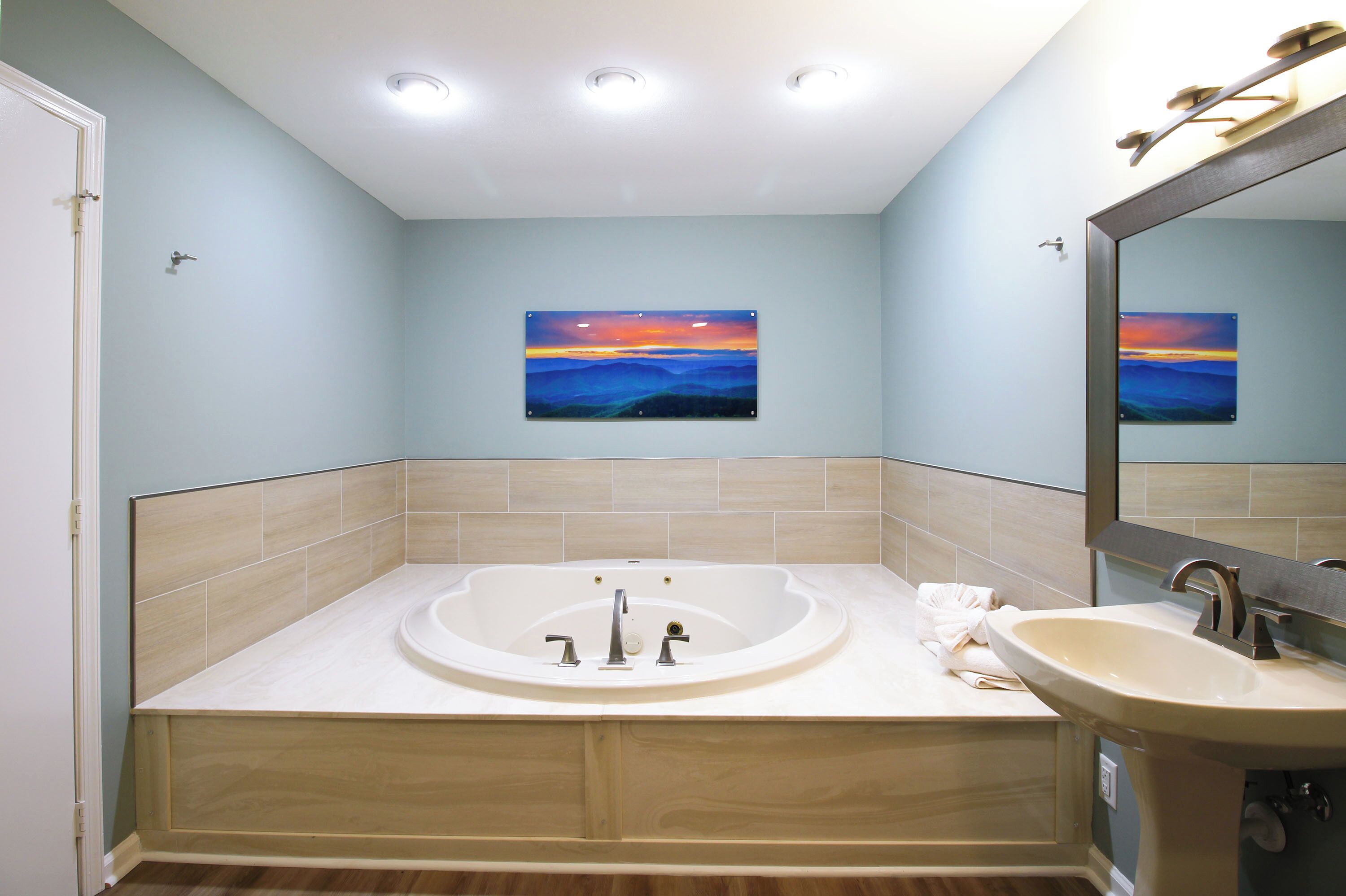 Un baño moderno con una bañera independiente, un lavamanos y dos cuadros colgados en la pared.