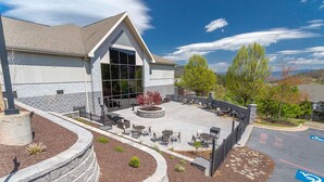 A building with a large glass entrance, outdoor seating area, and a parking lot with a handicapped parking space. - Mountain views, Balcony, Fireplace! (Mc Gaheysville)