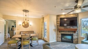 A dining area with a table and chairs, a fireplace, and a television mounted on the wall. - Full Kitchen, Mountain Views, Near Golf! (Mc Gaheysville)