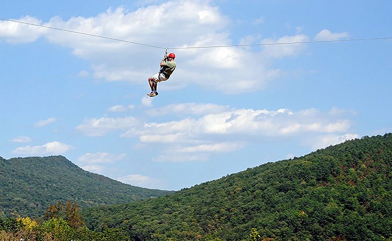 A person ziplining over a mountainous landscape.
