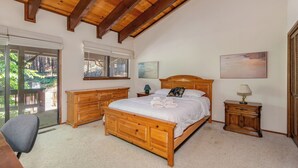 Ein Schlafzimmer mit einem hölzernen Bett, einem Nachttisch, einer Kommode und einem Sessel.