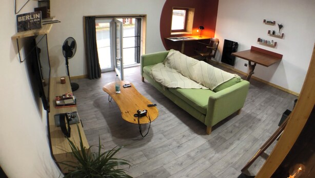 A compact living space with a green sofa, a wooden coffee table, a small desk, and a shelving unit.