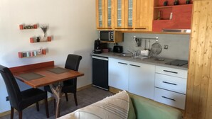 A compact kitchen with a dining table, chairs, a dishwasher, and wooden cabinets.