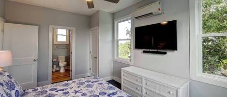 A bedroom with a bed, a ceiling fan, a TV, and a dresser.
