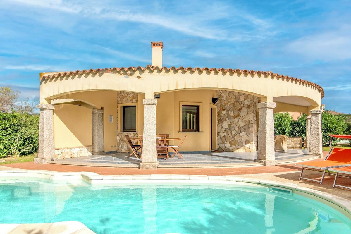 A villa with a swimming pool, outdoor seating, and a stone facade.