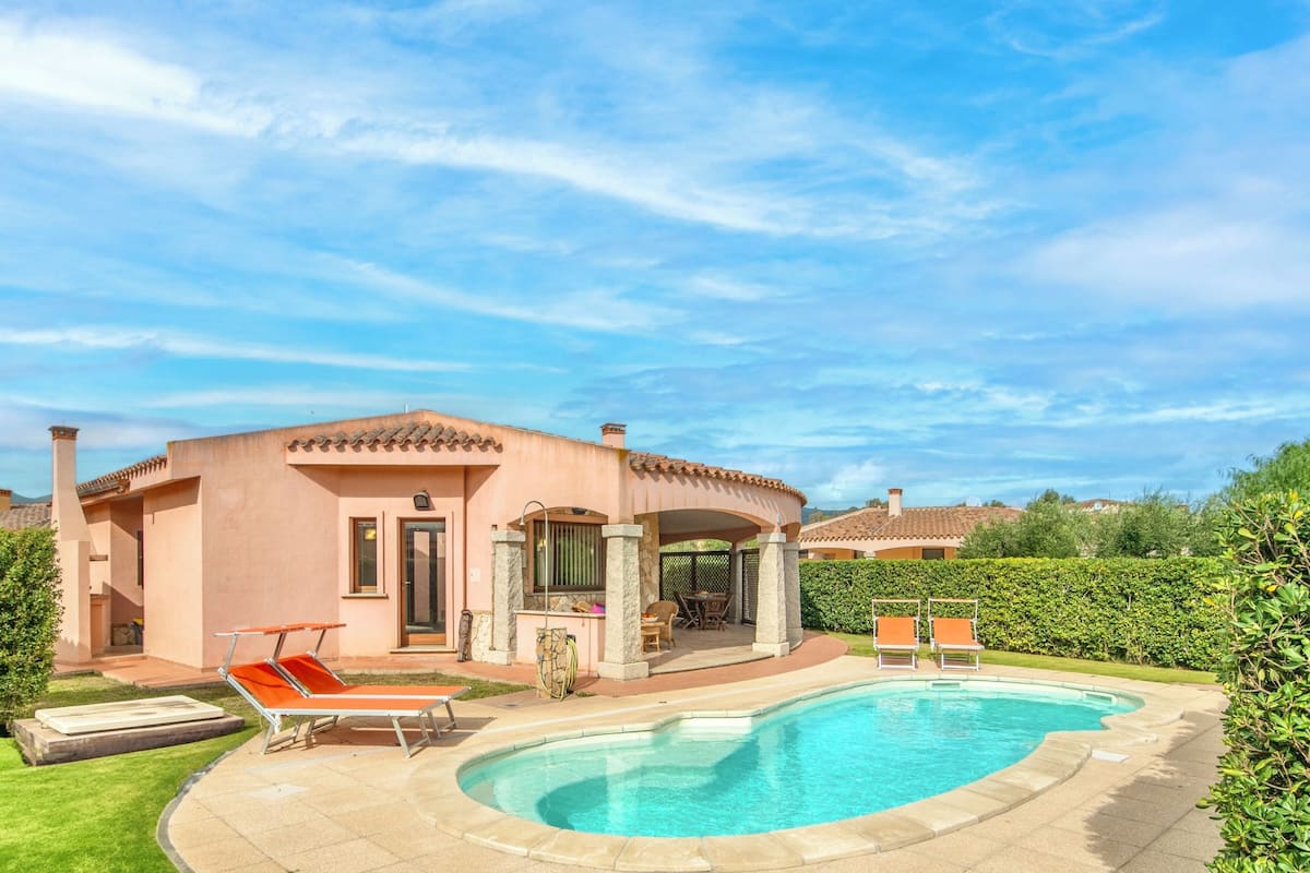 A house with a swimming pool, outdoor seating, and a well-maintained garden.