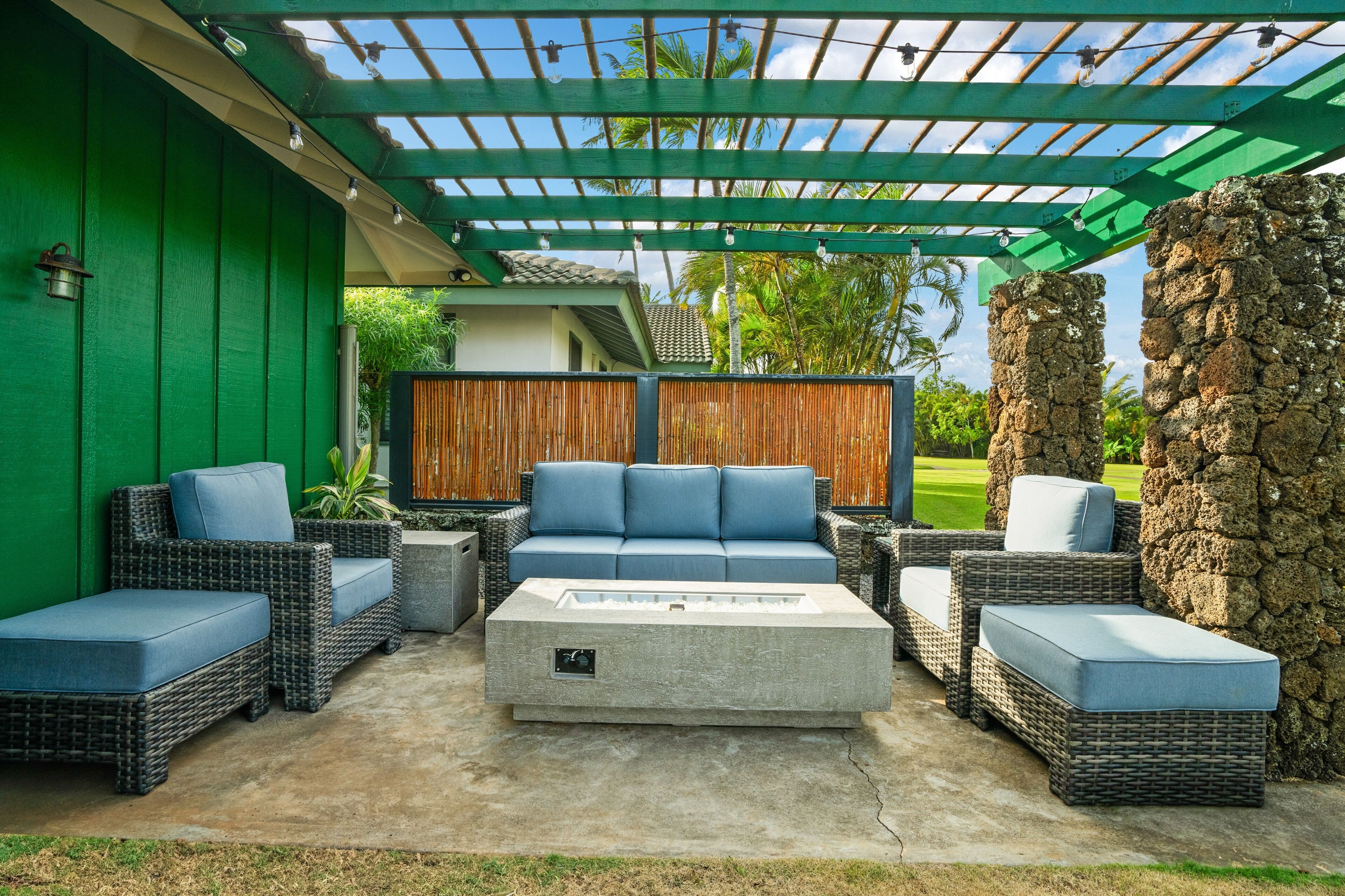 An outdoor patio with wicker furniture, a stone pillar, and a green pergola.