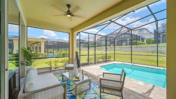 Relax by the pool in this serene outdoor space, featuring a sofa, chairs, and a glass table.