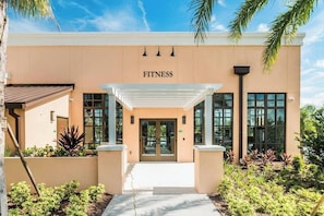 A modern building with a 'FITNESS' sign above the entrance, featuring a covered walkway and glass doors. - Elegant Family Home w/ Pool, Game Room, Themed Bedrooms (Kissimmee)