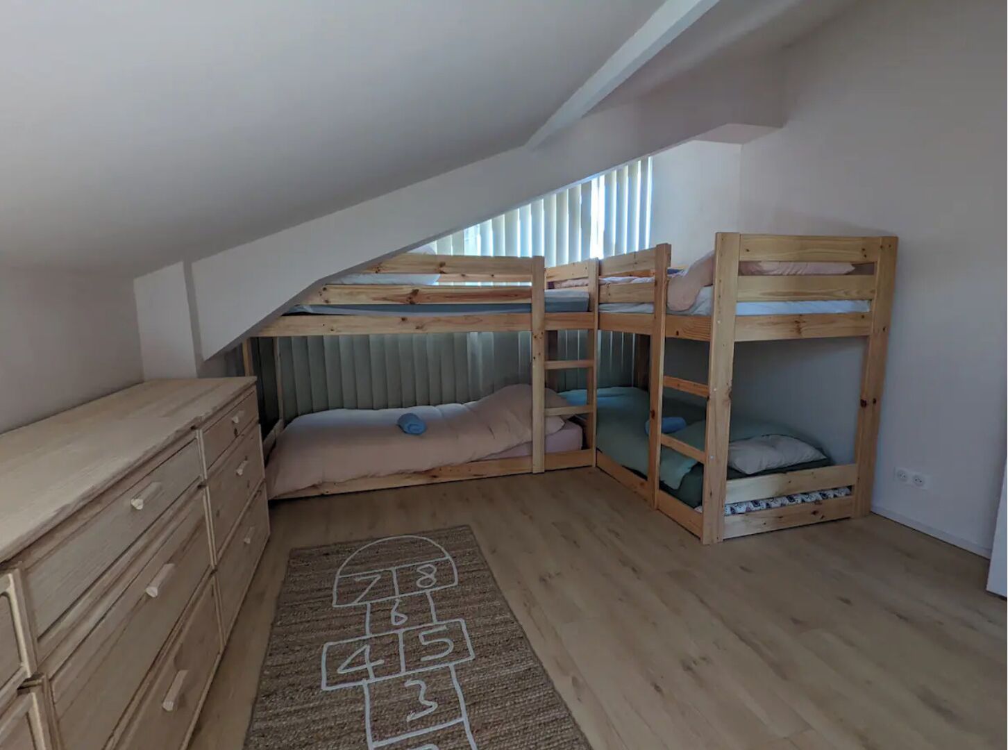 A loft bedroom with a bunk bed, a dresser, and a play mat.