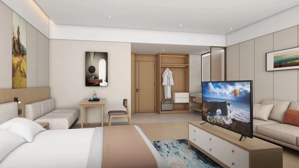 Ett modernt hotellrum med en säng, en TV, ett skrivbord och en sittgrupp.