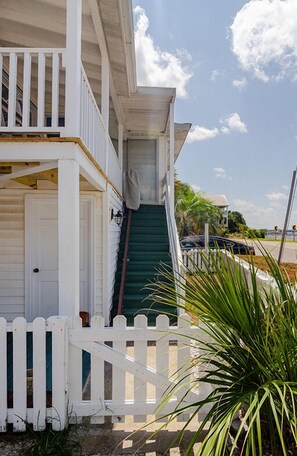 Stroll up the charming green staircase to this two-story residence, surrounded by a white picket fence and lush surroundings.