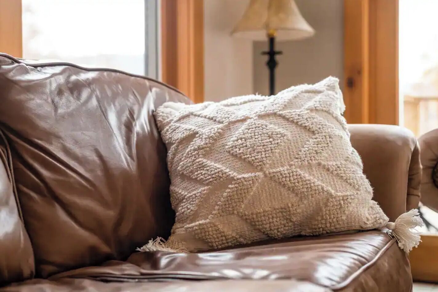 Un canapé en cuir marron agrémenté d’un coussin blanc à texture.