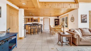 Een ruime woonkamer met houten plafond, een eettafel en een leren bank.