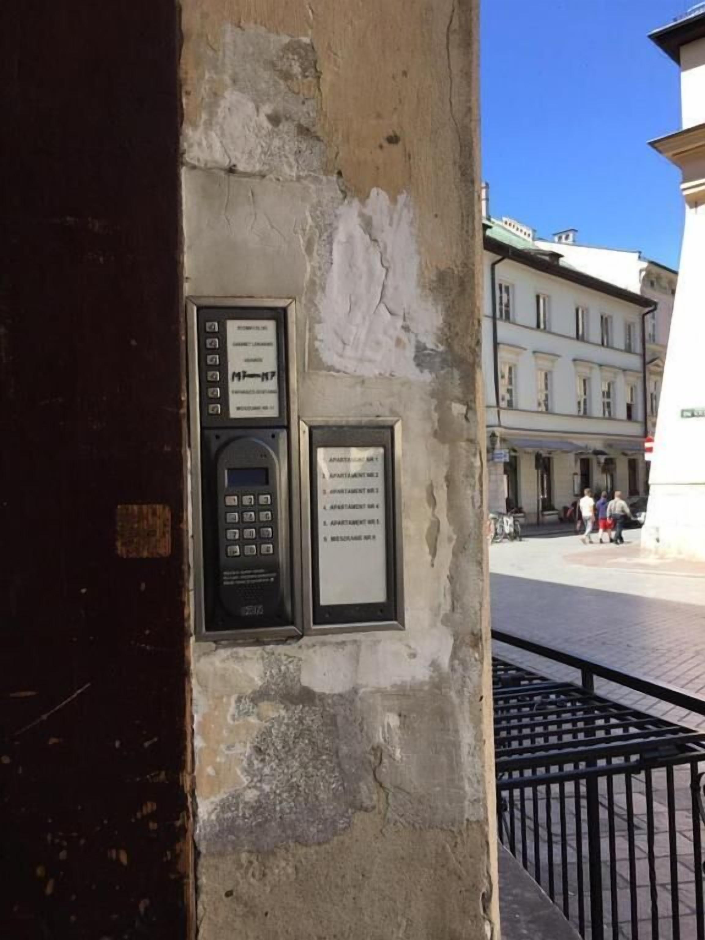 A wall with a keypad and a sign listing apartment numbers.
