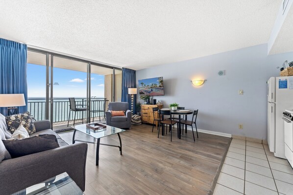 A modern apartment with a balcony, a dining area, a kitchen, and a living room.