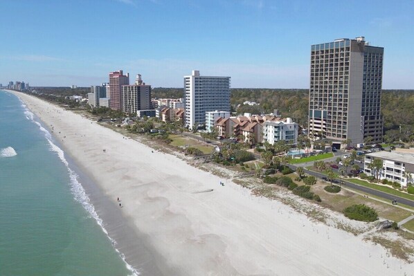 A coastal hotel area with beachfront access, multiple high-rise buildings, and a sandy beach.