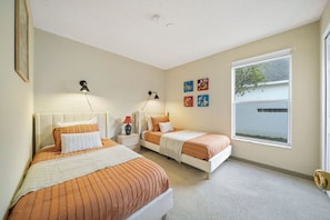 Quarto com duas camas, janela e decoração nas paredes.