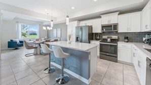 A modern kitchen with white cabinets, stainless steel appliances, and a central island with bar stools.