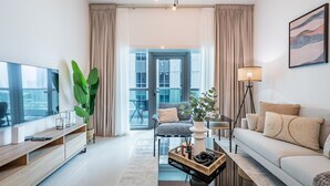Un salon moderne avec un téléviseur à écran plat, un canapé, une table basse et une grande plante.