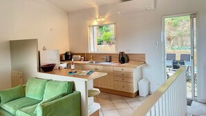Um espaço compacto com cozinha compacta, sofá verde e janela que traz luz natural.