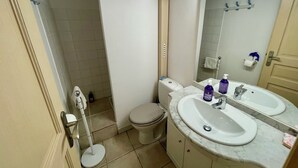 Casa de banho com sanita, bidé e lavatório com espelho.