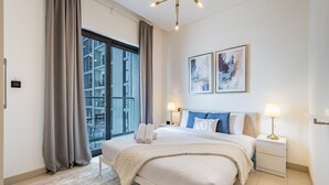 Ein modernes Hotelzimmer mit einem großen Bett, zwei Nachttischlampen und einem Kunstwerk an der Wand.