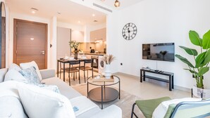 Ein modernes Wohnzimmer mit Sofa, Couchtisch und Essbereich mit Stühlen und Tisch.