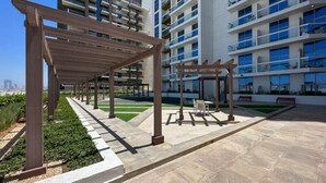 Un espace extérieur moderne doté de pergolas, de coins salon et offrant une vue sur des immeubles résidentiels de grande hauteur.