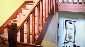 Un escalier en bois avec une rampe, une porte en haut et une fenêtre avec des plantes en dessous.
