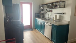 Una cocina con gabinetes color turquesa, un refrigerador negro, un microondas y una cafetera.