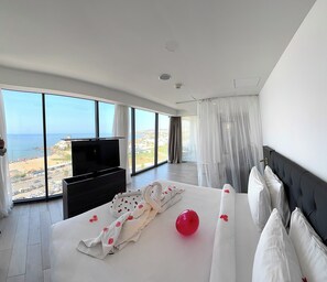 Una habitación de hotel moderna con una cama grande, un televisor de pantalla plana y vista al mar.
