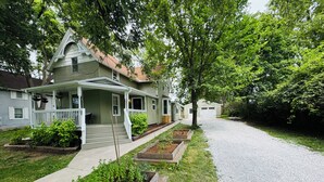 Een tweelaags huis met een veranda, een grindpad en een keurig onderhouden tuin.