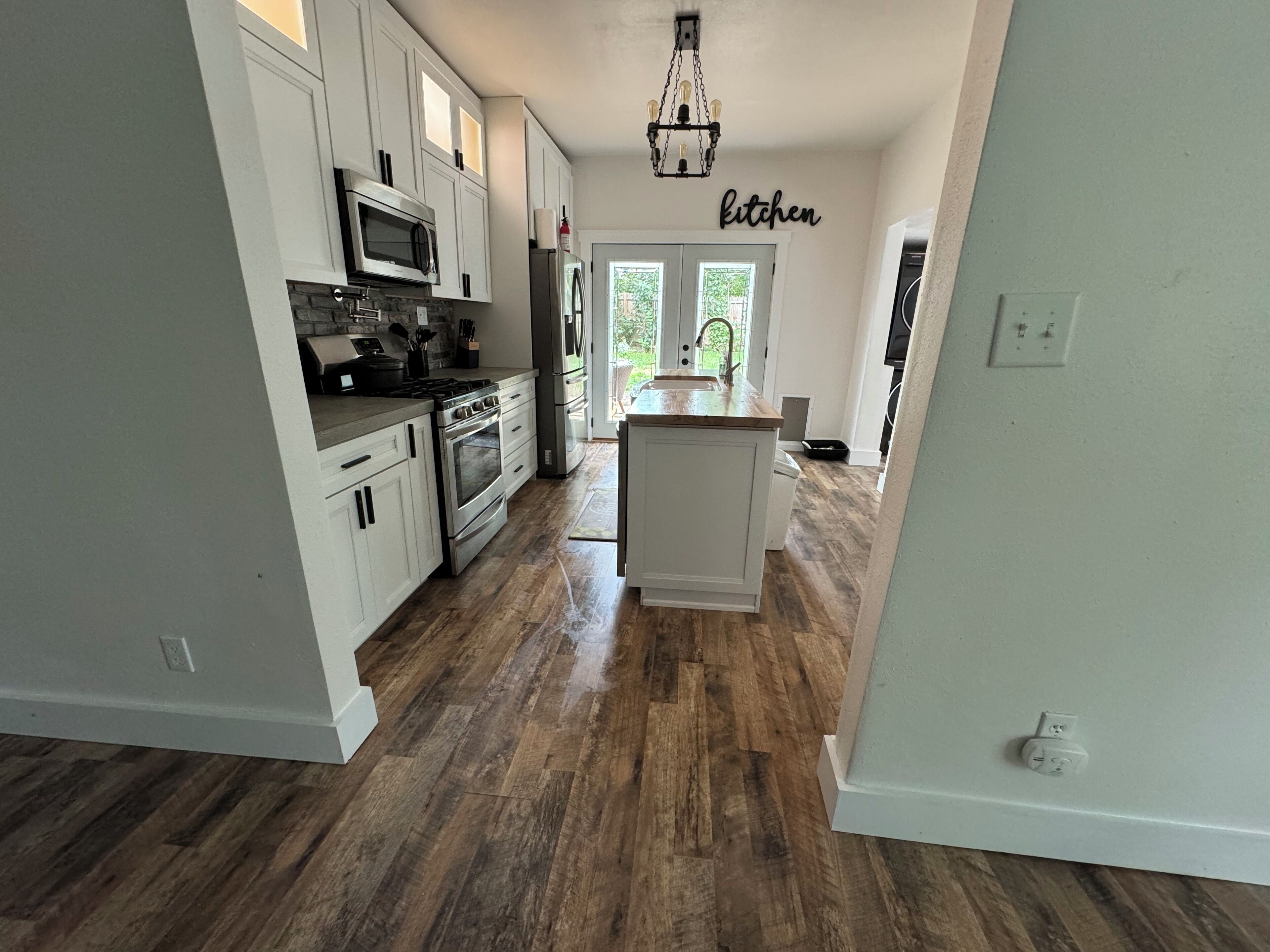 A modern kitchen with white cabinetry, stainless steel appliances, and a central island.