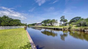 Een rustige rivier met een houten looppad aan de linkerkant, omgeven door grasoevers en bomen.