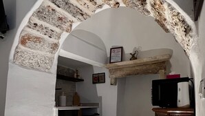 Eine Küche mit einem Steingewölbe, einem Kühlschrank, einer Mikrowelle und einem Holzschrank.