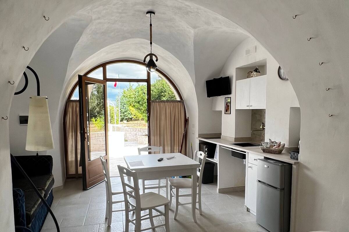 Una habitación acogedora y de concepto abierto con cama, mesa de comedor y zona de cocina.